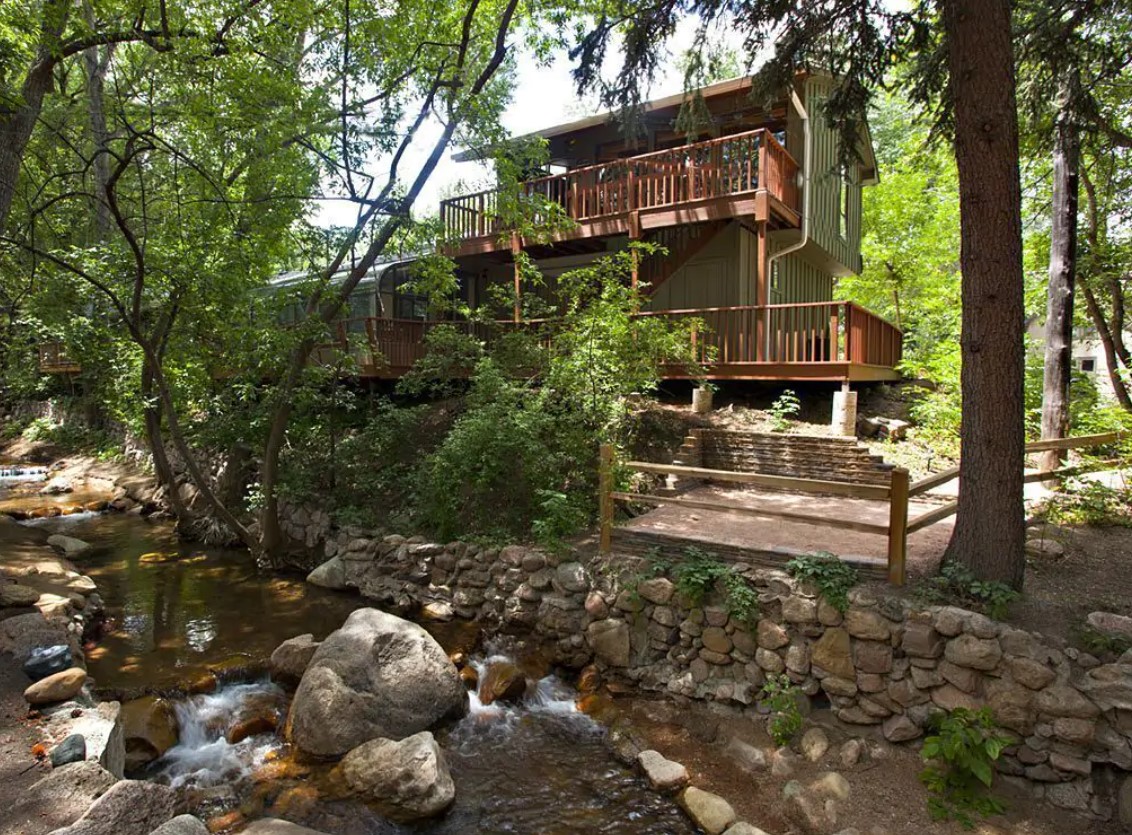 A bungalow style house hidden amongst the trees with a small creek in the backyard