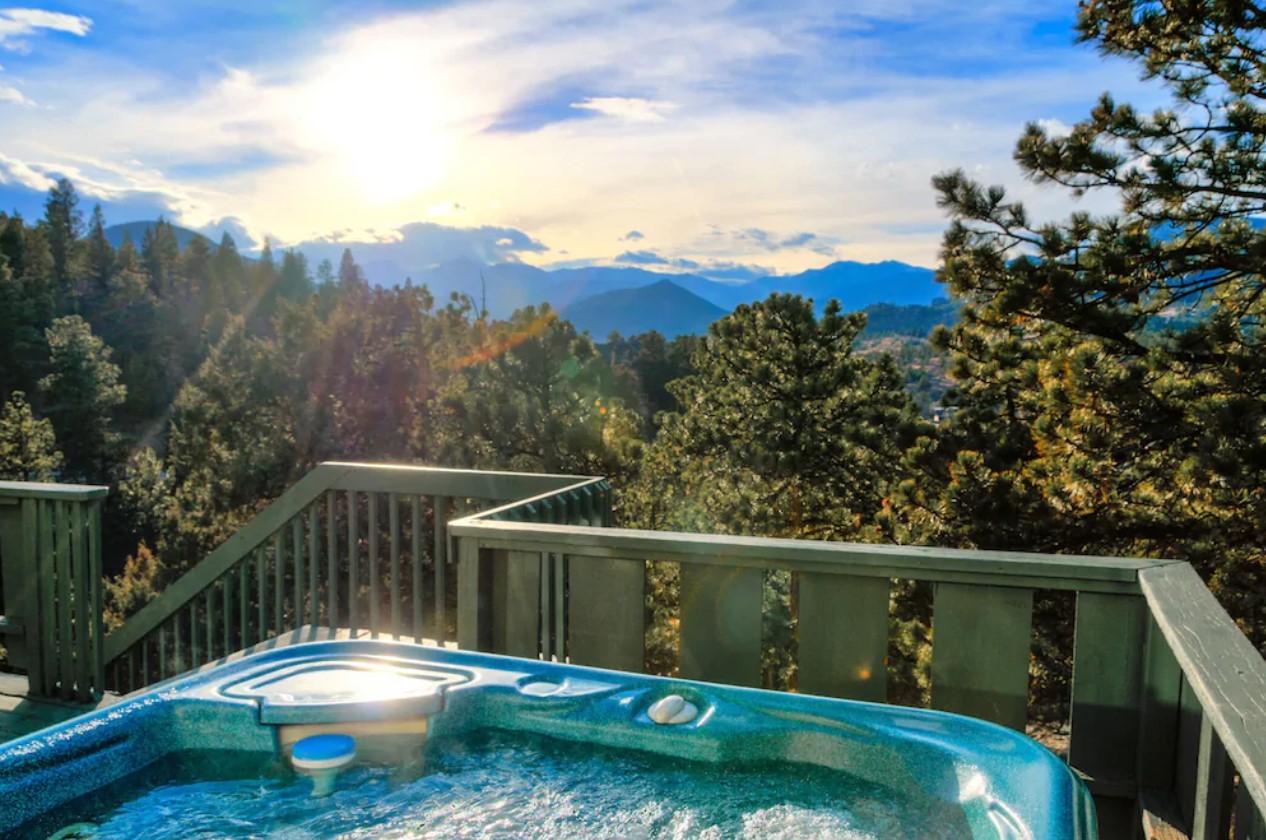 The edge of a hot tub on a deck with views looking out onto the Continental Divide at sunset a great VRBO in Colorado