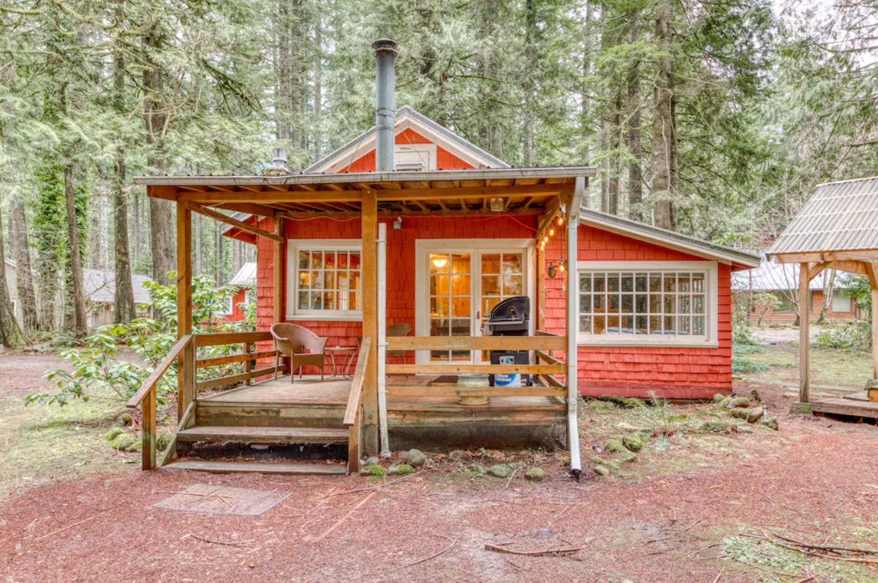 A red cedar shingled single level cabin in the woods of Oregon with plenty of windows