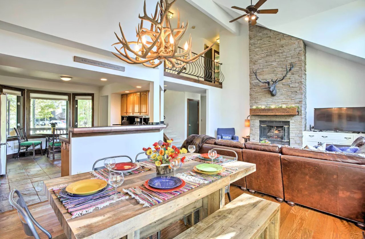 The interior of a upscale mountain home with a large couch, and dining room, and large fireplace VRBO in Colorado