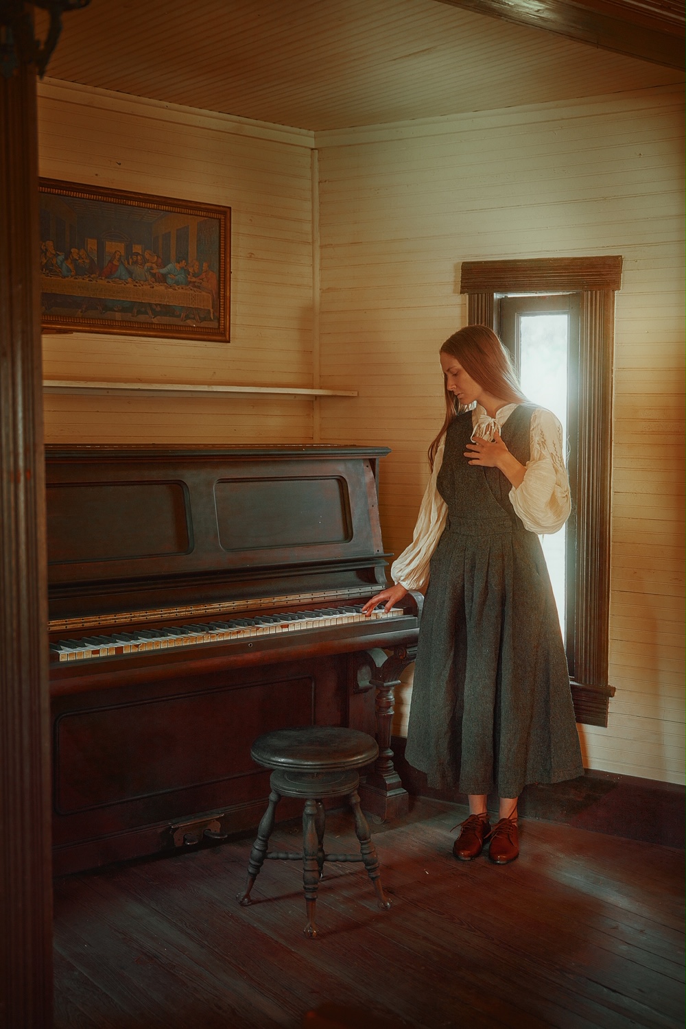 A woman standing by a piano wearing a grey linen dress