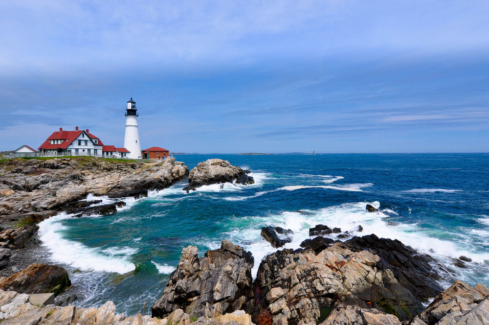 A lighthouse on a rocky coast in Maine on a sunny day