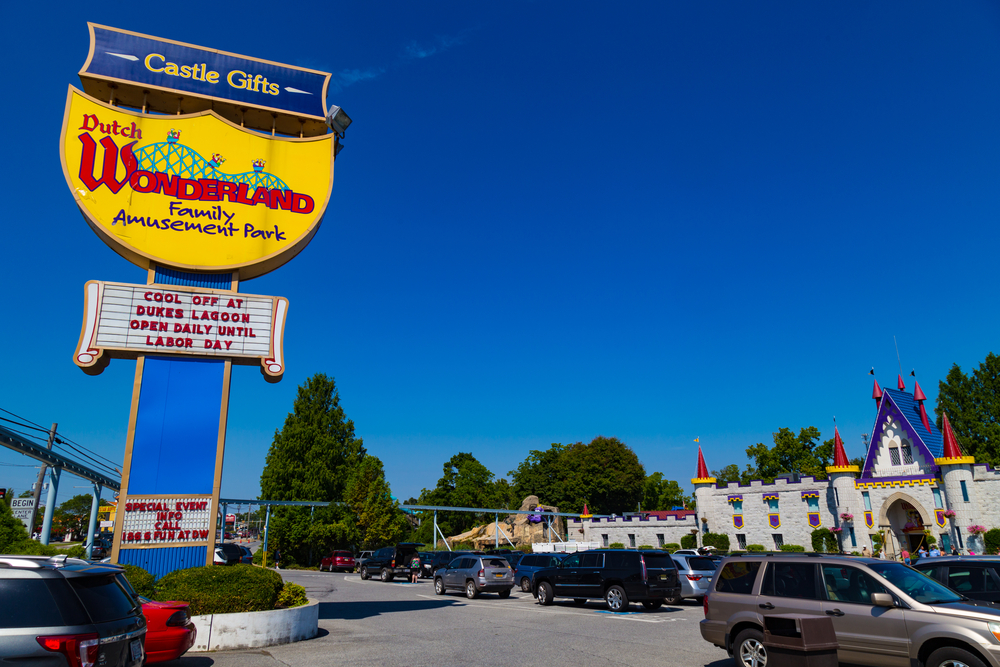 The main entrance to Dutch Wonderland, a amusement park in Amish country Pennsylvania. The sign is yellow and kind of shaped like a crown. At the entrance of the park is a large castle.