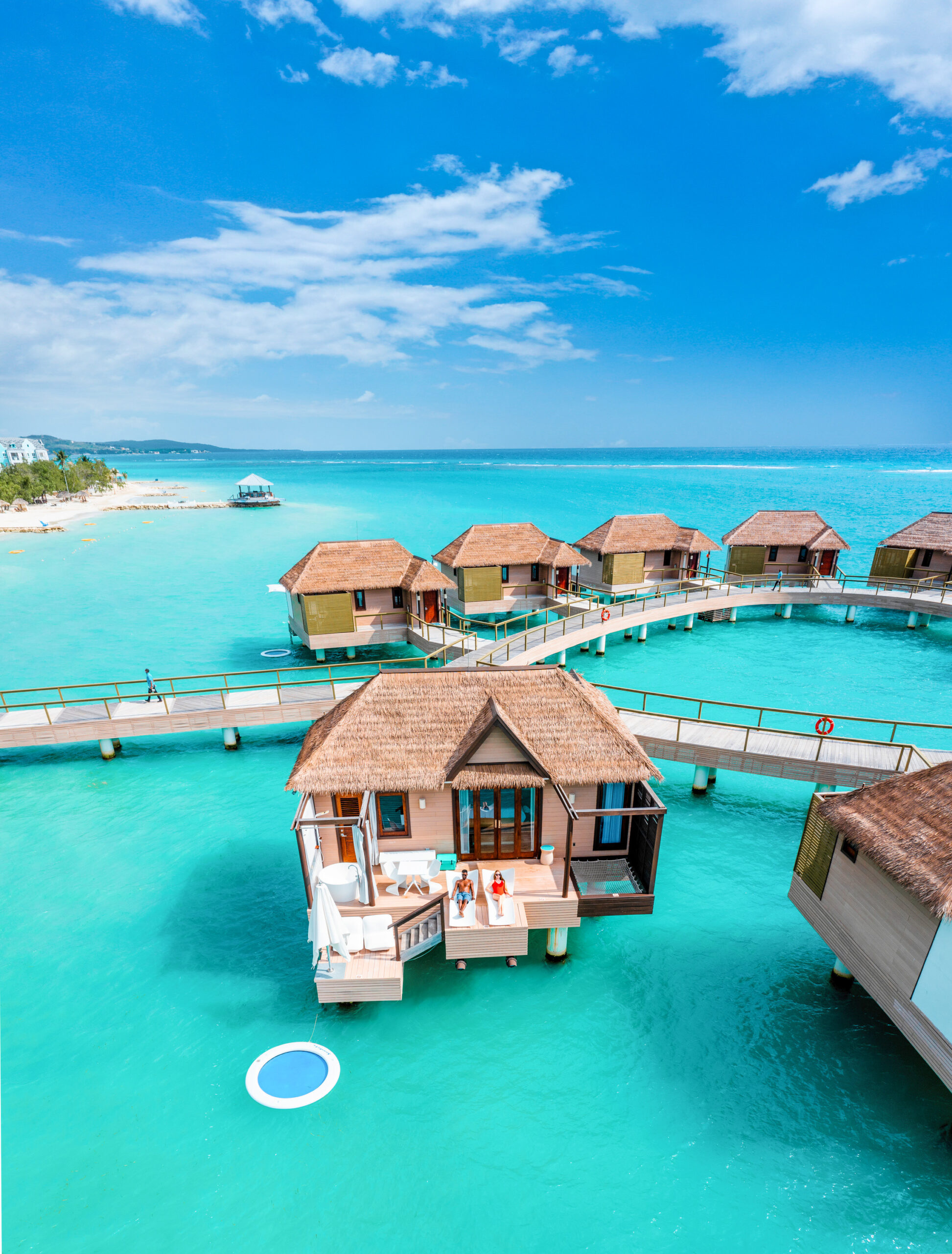 drone photo of couple sitting on an overwater bungalow in jamaica at Sandals South Coast in the caribbean