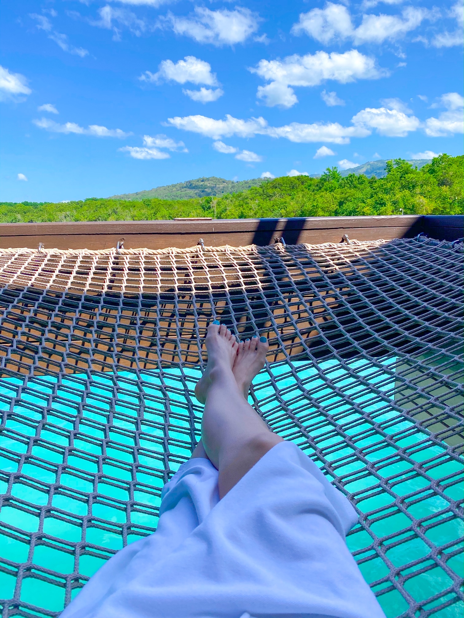 sitting in a netting over the ocean at an overwater bungalows in jamaica
