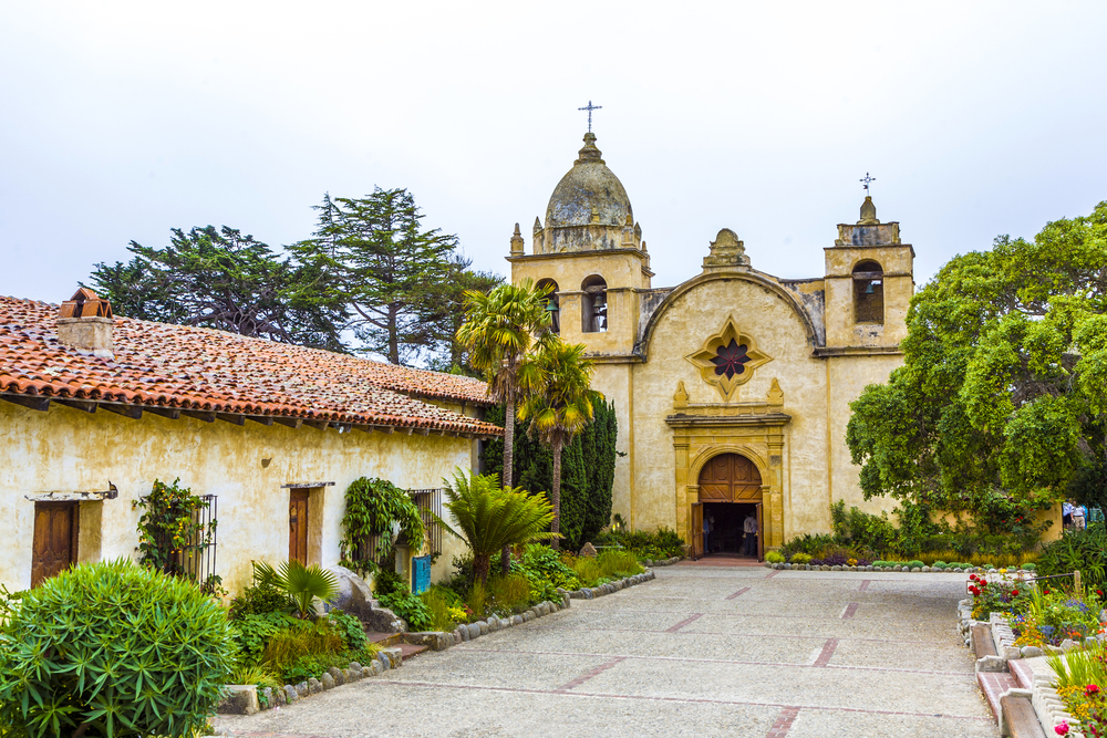 The exterior and courtyard of the historic Carmel Mission. It is an old Spanish style mission with Spanish colonial architecture. A great starting point for a Big Sur road trip