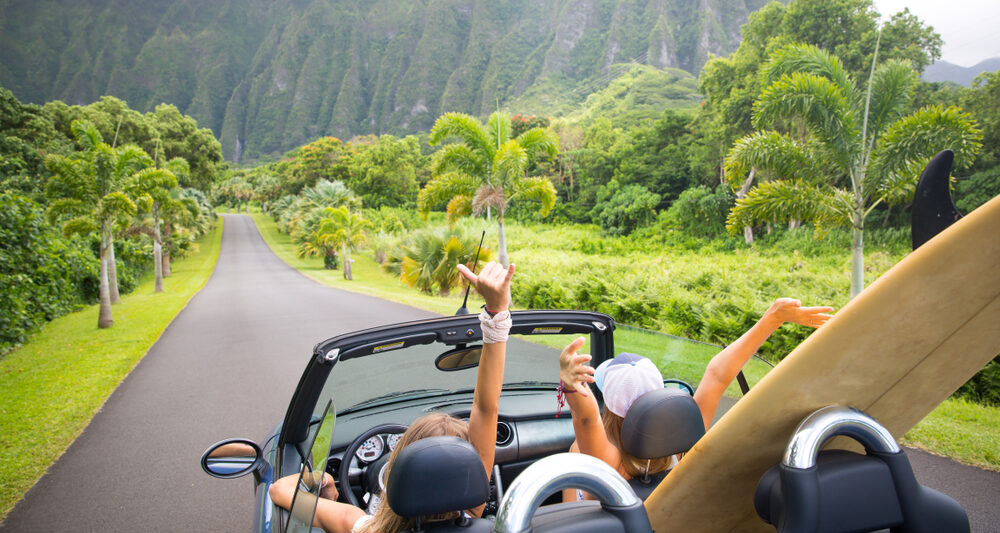 women in car in Hawaii with surfboards