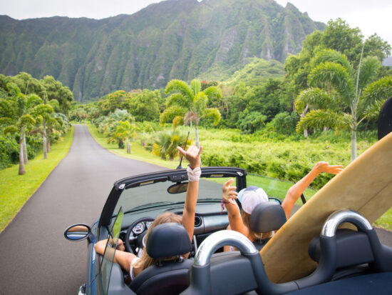 women in car in Hawaii with surfboards