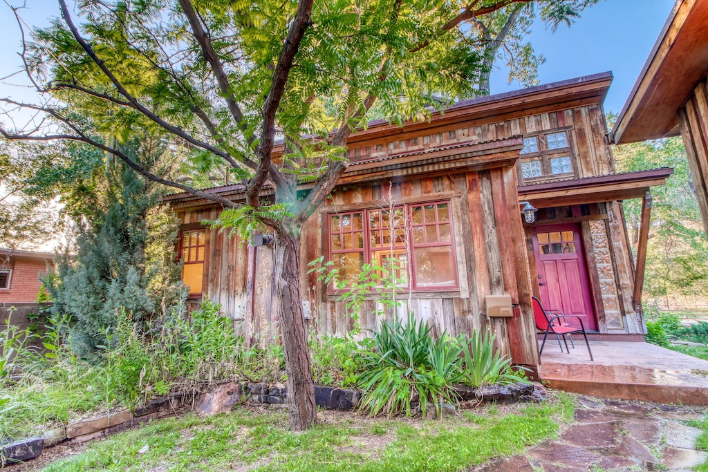 Exterior and red front door of the Creekside Guest Cottage. 