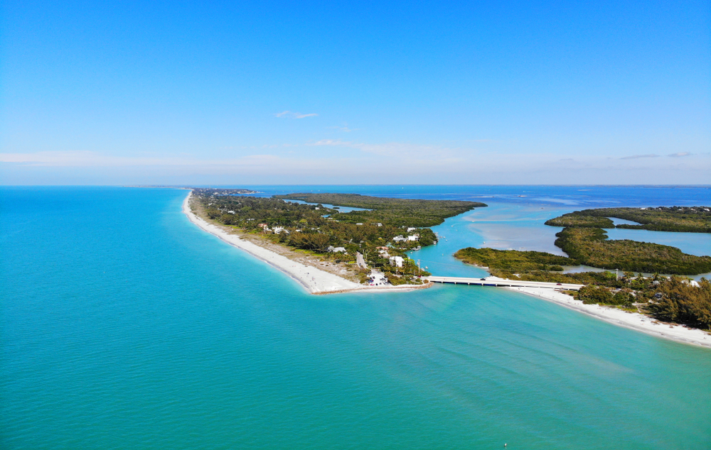 An aerial view of some Florida islands in the USA. You can see lush greenery, white sandy beaches, and crystal blue water. 