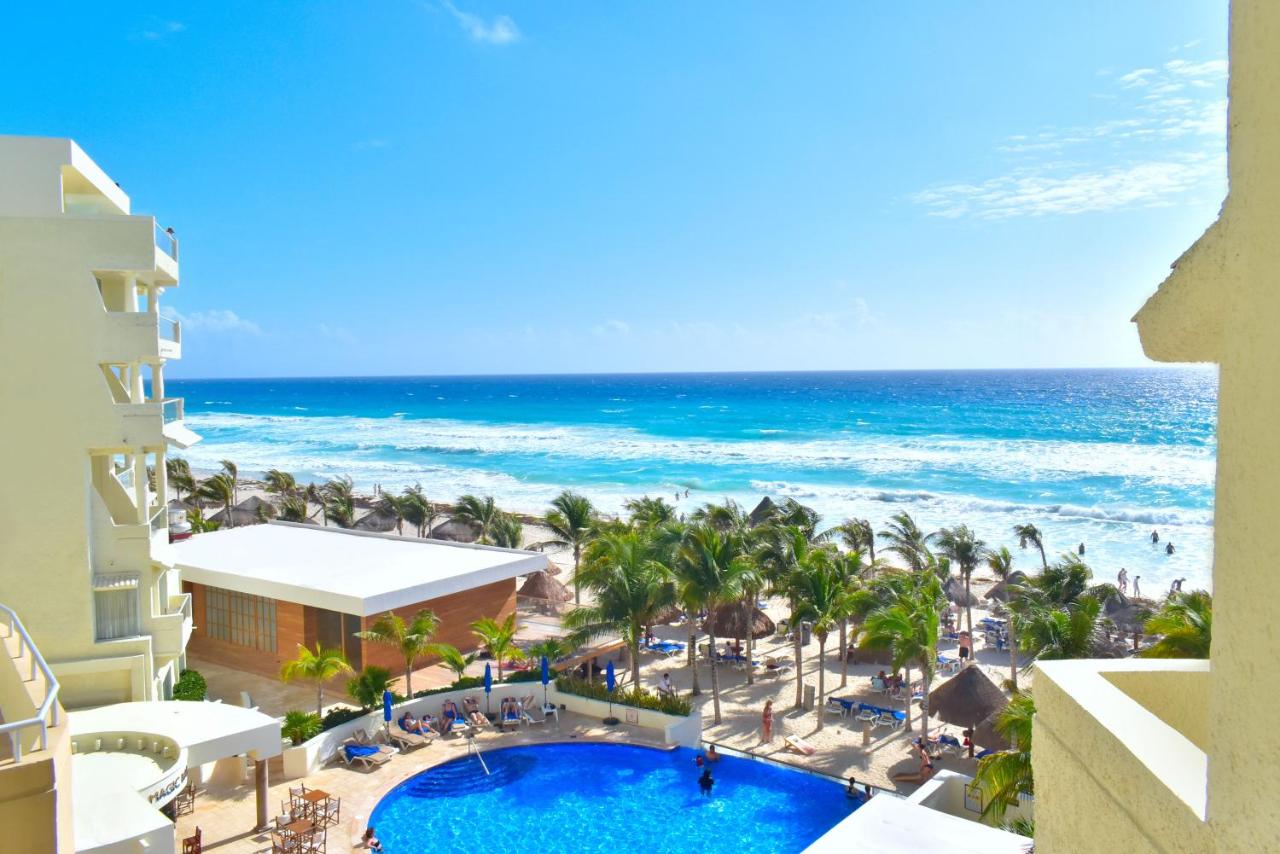 The view of a large pool, the beach, and palm trees from a room at an all-inclusive resort in Mexico. 
