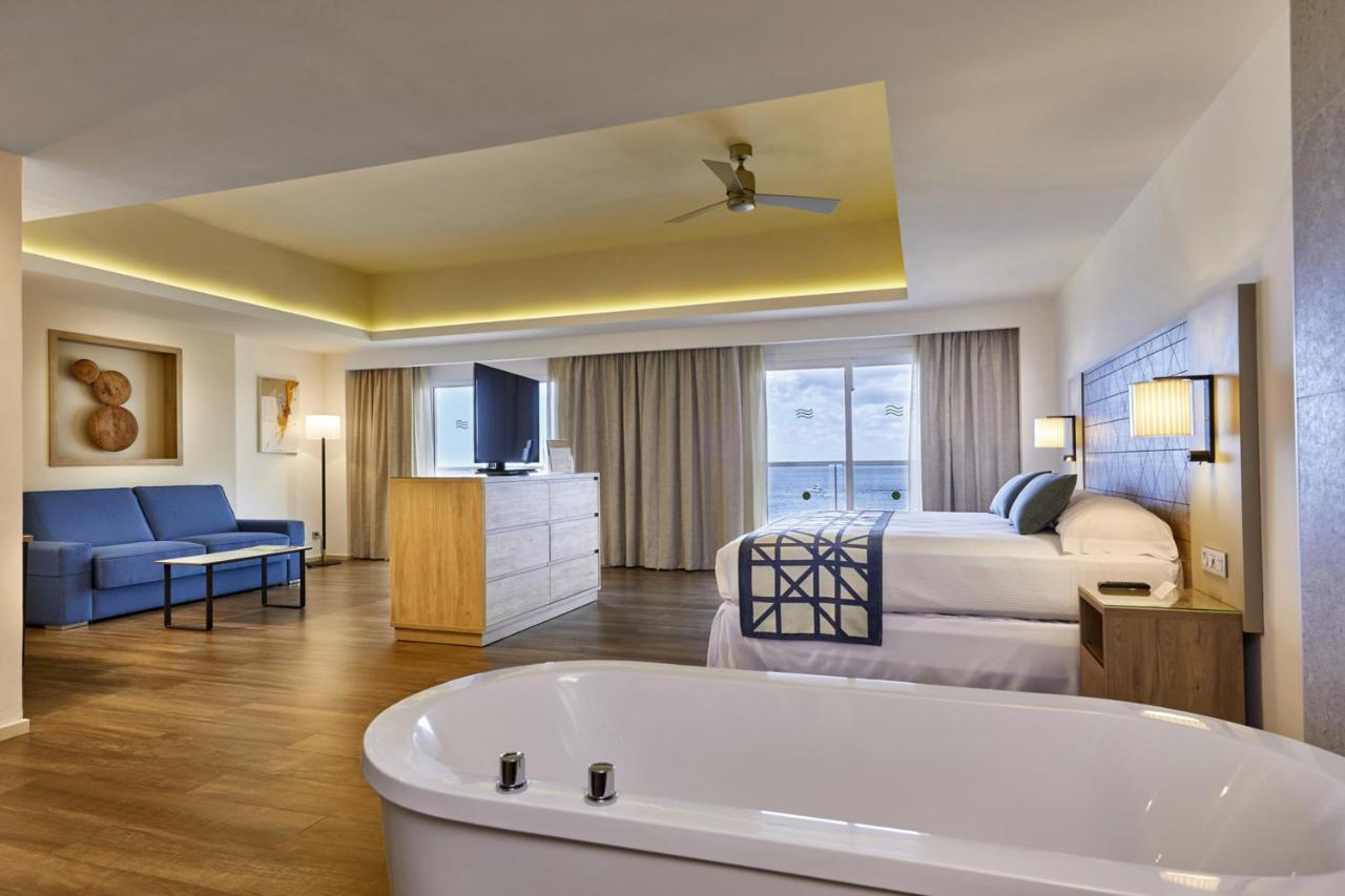 A suite that has a large tub, a seating area, a king sized bed, and a private balcony. 