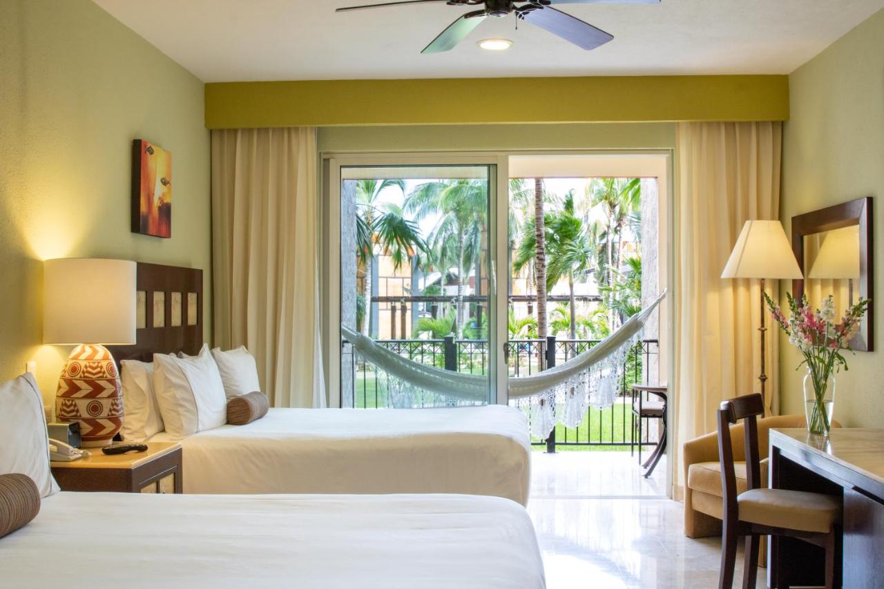 The inside of a double suite at an all-inclusive resort that has a balcony with a hammock on it. 