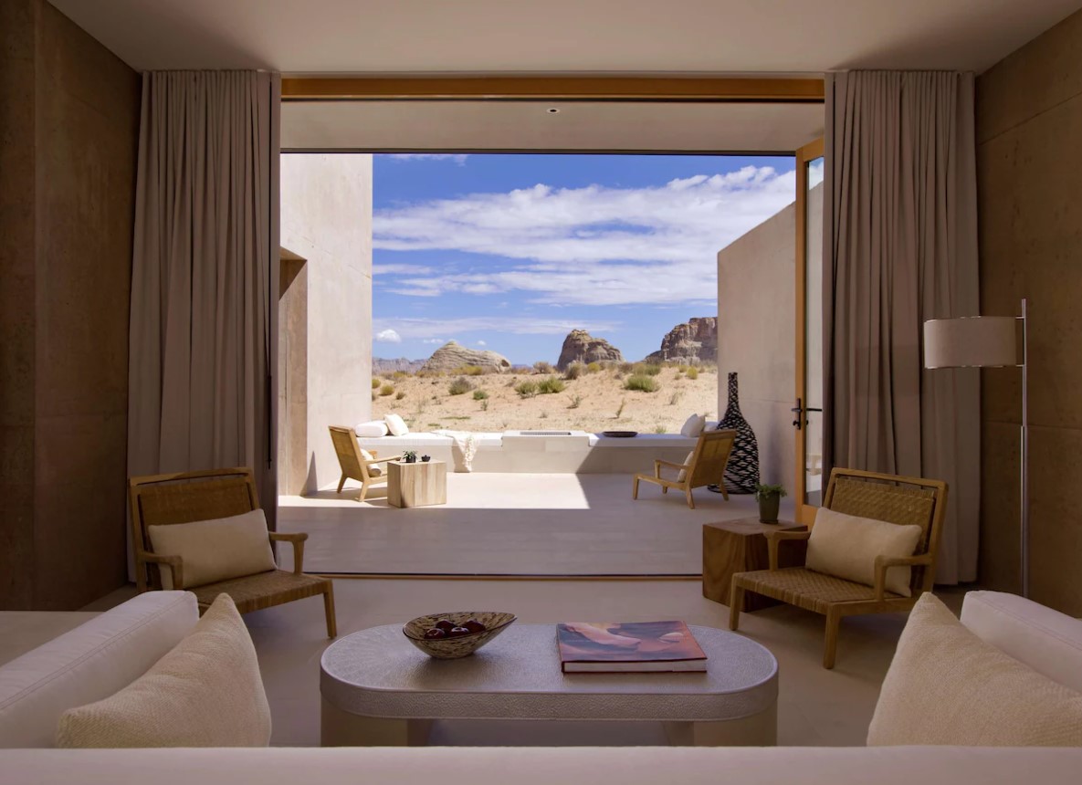 The view out onto a balcony in one of the best luxury hotels in the USA. The view is of the desert and you can see patio furniture as well as furniture in the room. 