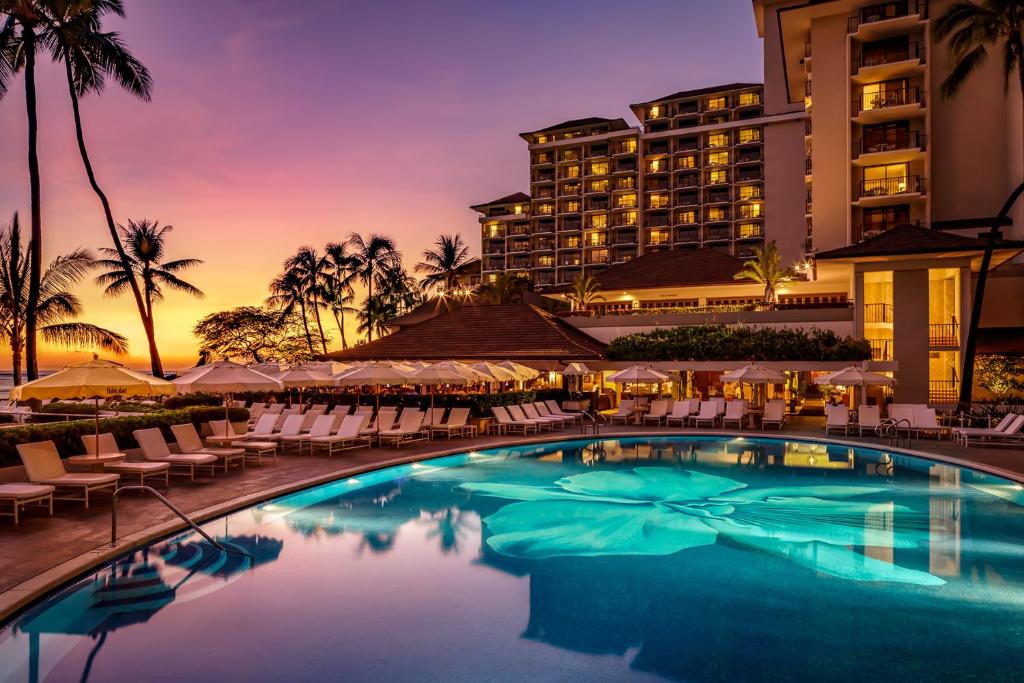 hotel pool at sunset with hotel in background in an article about best luxury hotels in Hawaii 