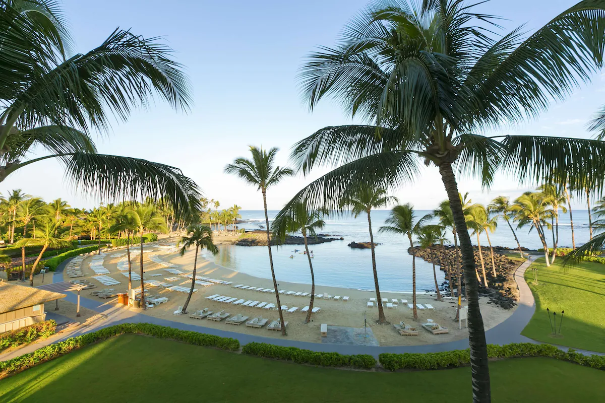 deck by a ocean pool surrounded by palm trees at one of the the best luxury resorts in Hawaii. 
