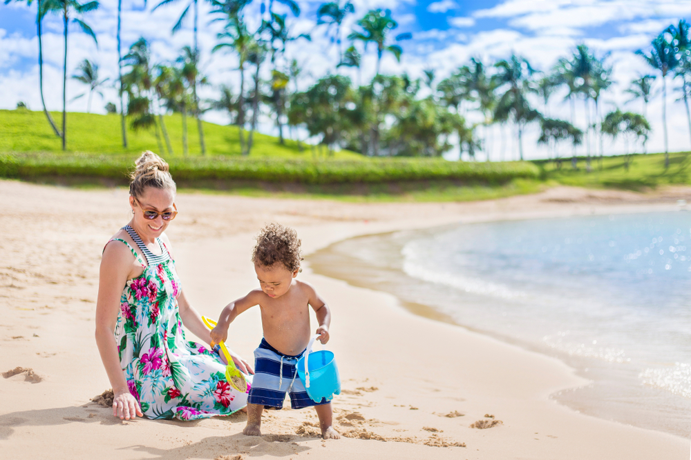 A mother on the bech with her son bulding sandcastels. In an article about best luxury hotels in Hawaii