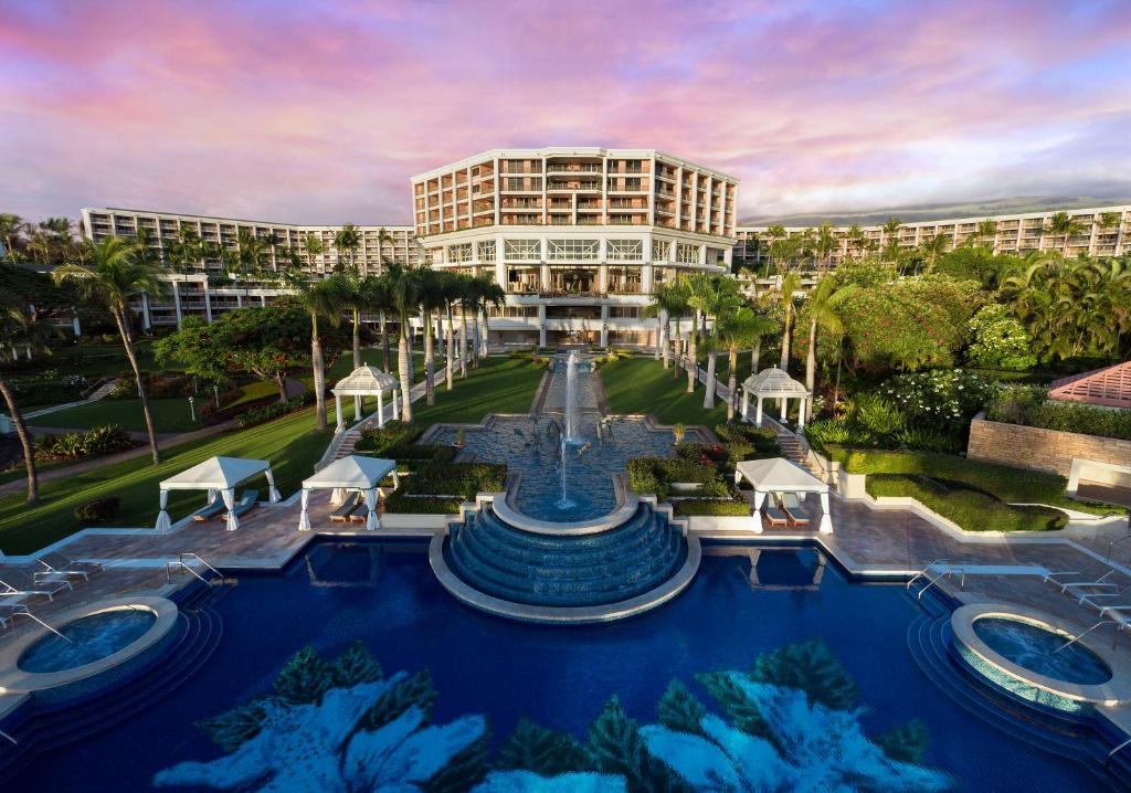 Hige pool with fountain leading to a hotel building. 