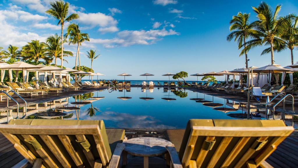 pool surrounded by chairs and umberellas overlooking the ocean.  