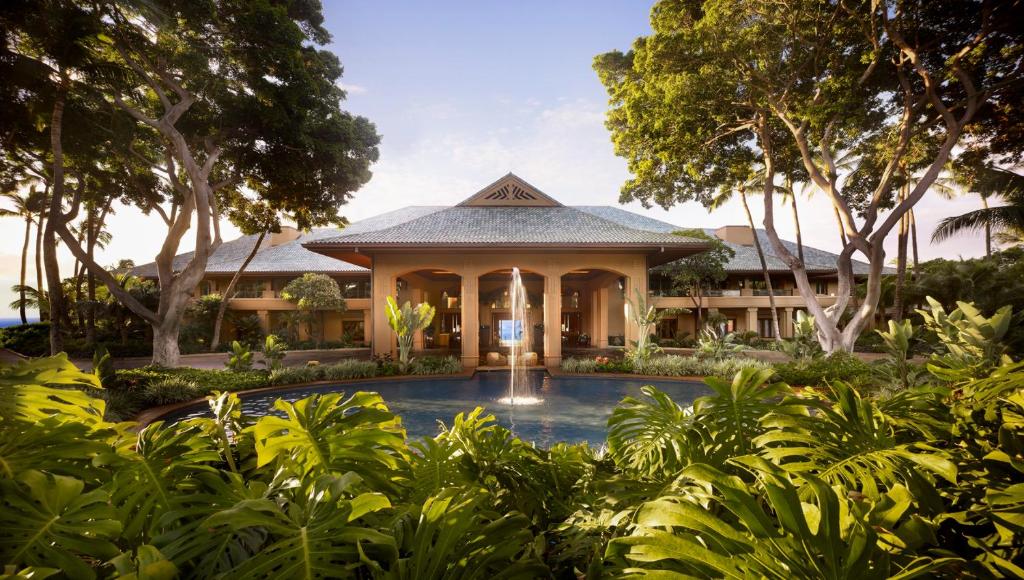 building with a pool and fountain in front and lush landscapping 