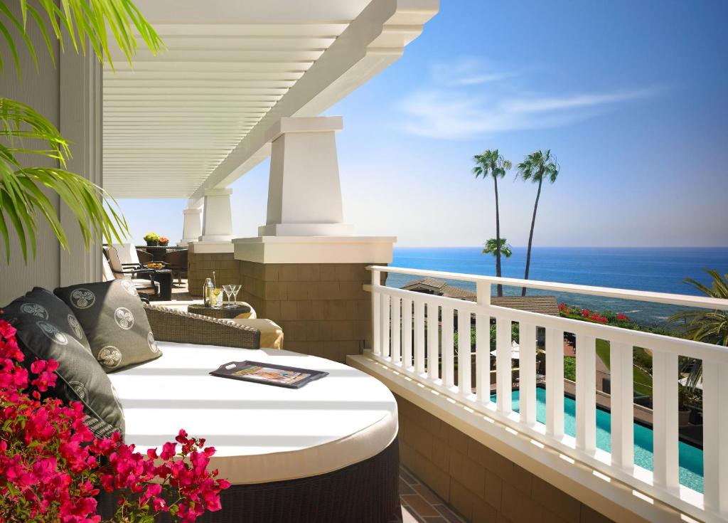 The balcony at a luxury hotel that has a large circular couch and looks out at a pool and the ocean. 