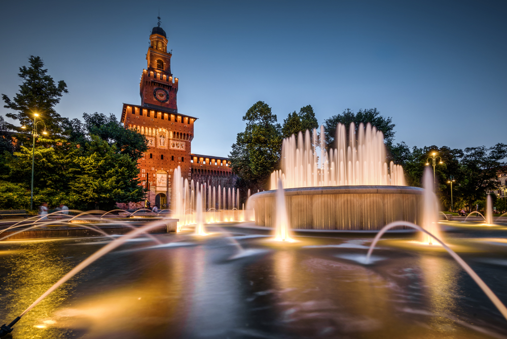 A fountain in front of Sforza Castle at night.