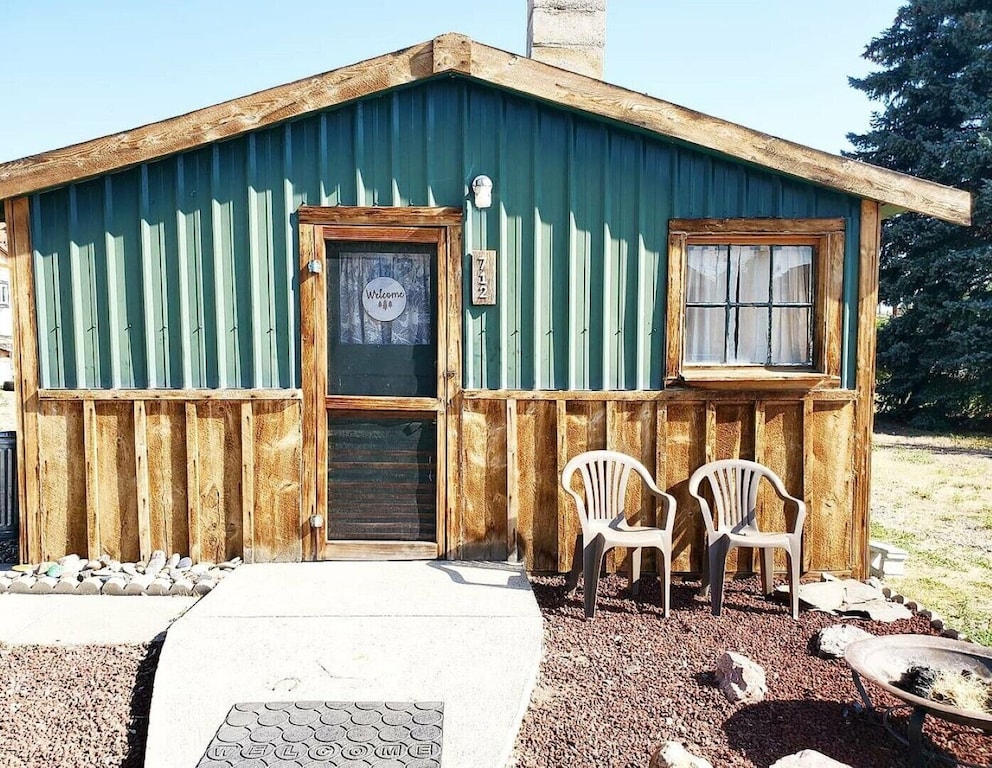 exterior of this small green and wood paneled cabin 