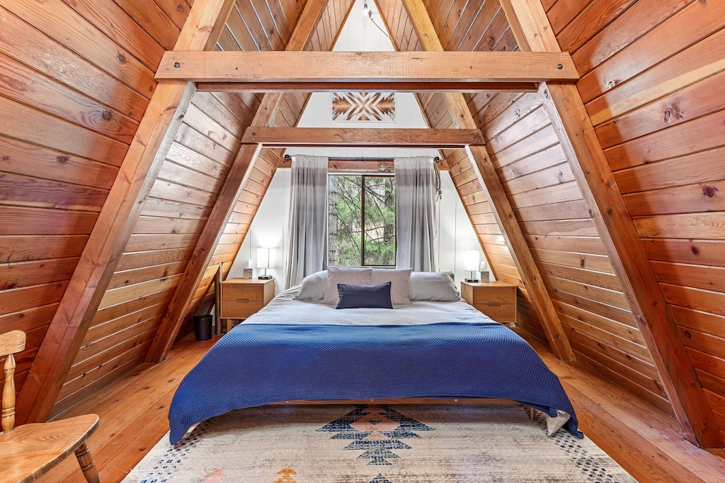 view of the queen bed in the peak of the A frame of this cabin. This is a great choice if you're looking for lakes in Oregon with cabins. 