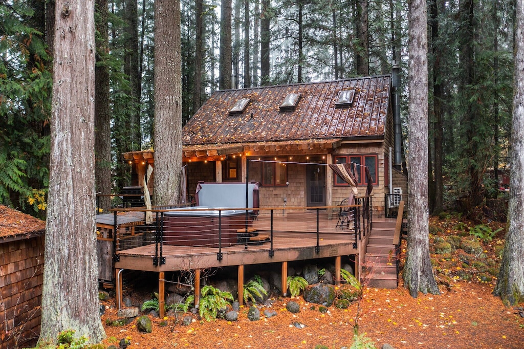 Exterior photo of the Mt Hood Cabin showing off it's skylights and spacious back deck including hot tub