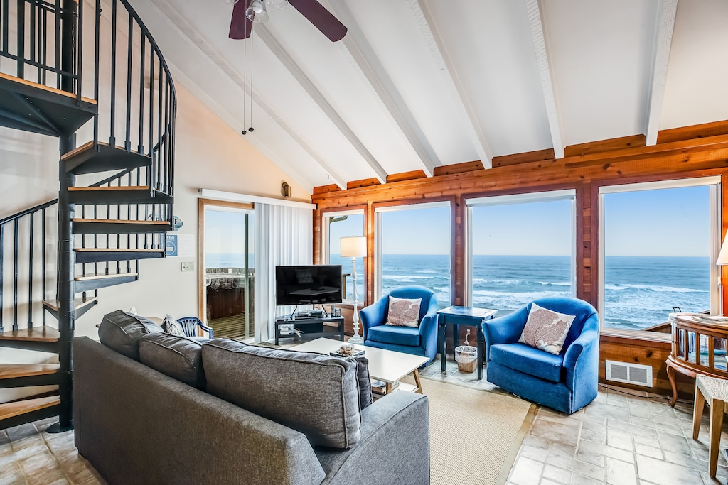 View of the spiral staircase to the loft and the big picture windows of this cabin in Oregon. 