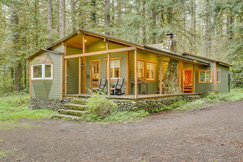 Olive green cabin with a spacious front porch featuring rocking chairs
