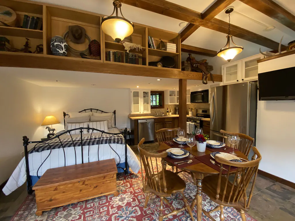Inside of one of the best cabins in Colorado showing a bed, table and kitchen in the background