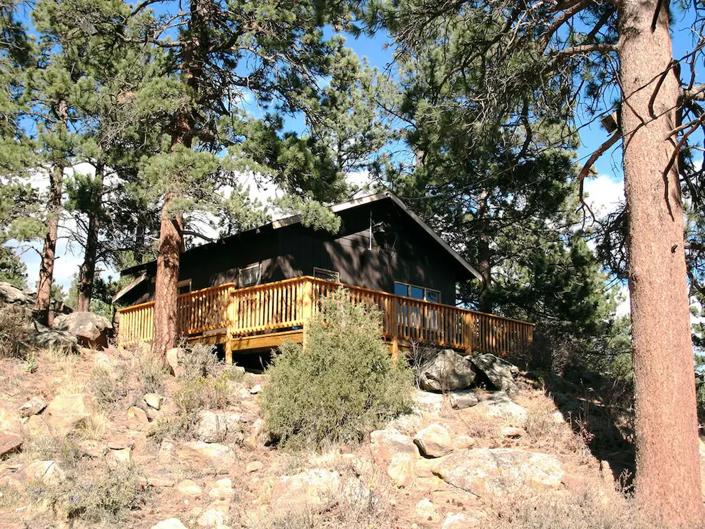 Cabin sitting on a rocky ledge amoung the trees