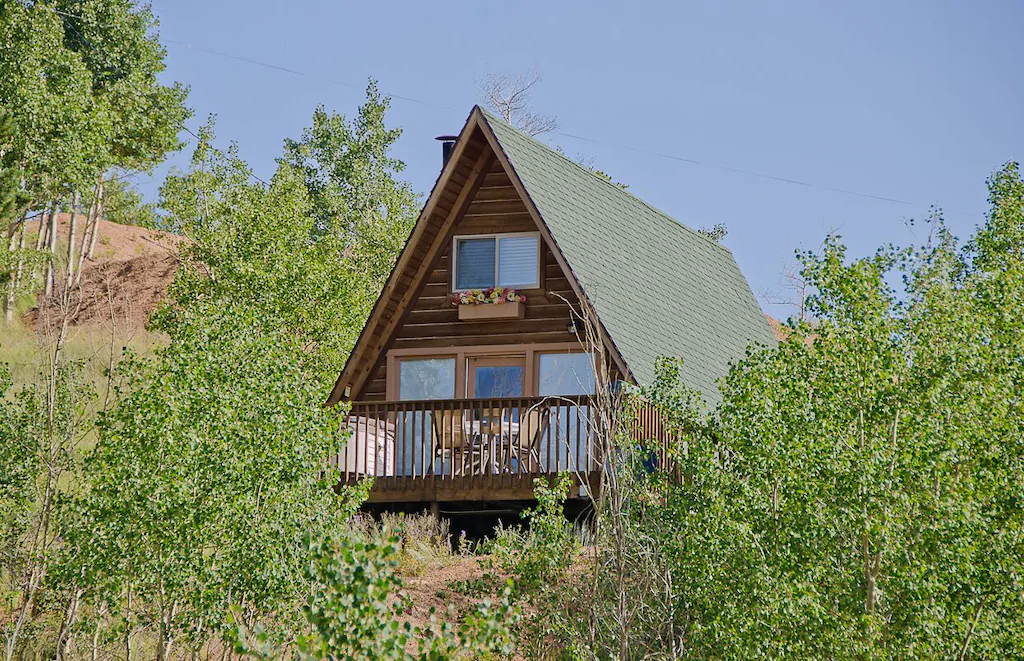 A frame log cabin viewed through the tress. 