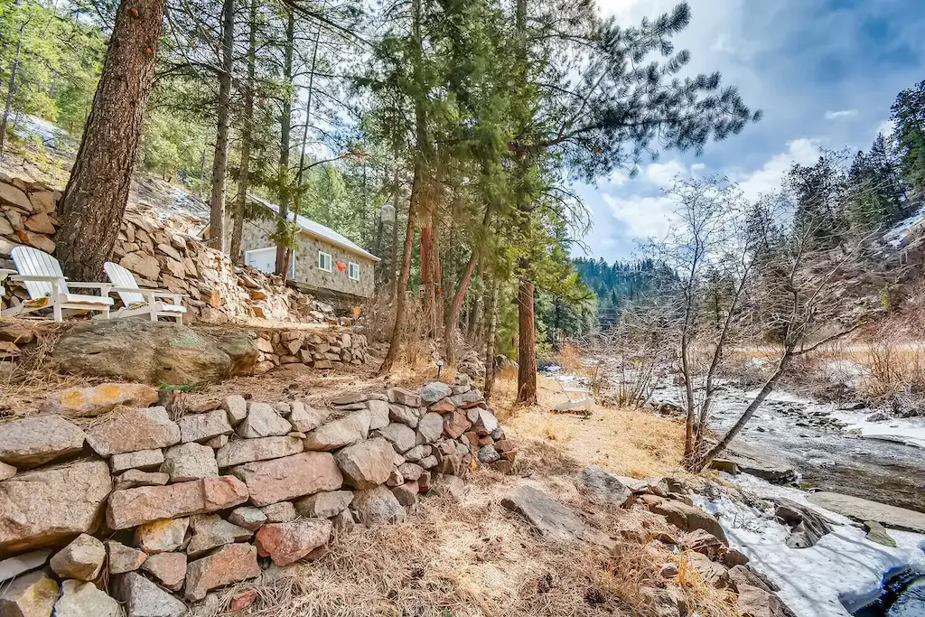 A cabin perched on a roack outcrop overlooking a stream in an asrticle about the best cabins in Colorado 