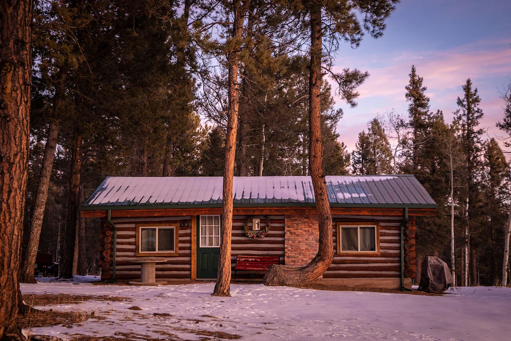 Retro log cabin in the woods with snow on the grounds 