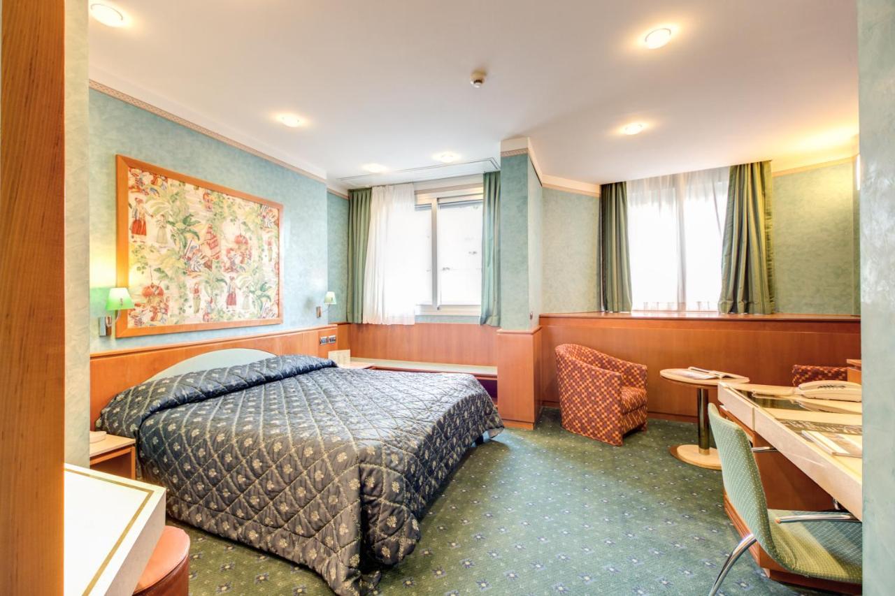 Colorful room at Brunelleschi Hotel with seating area, desk, and windows.