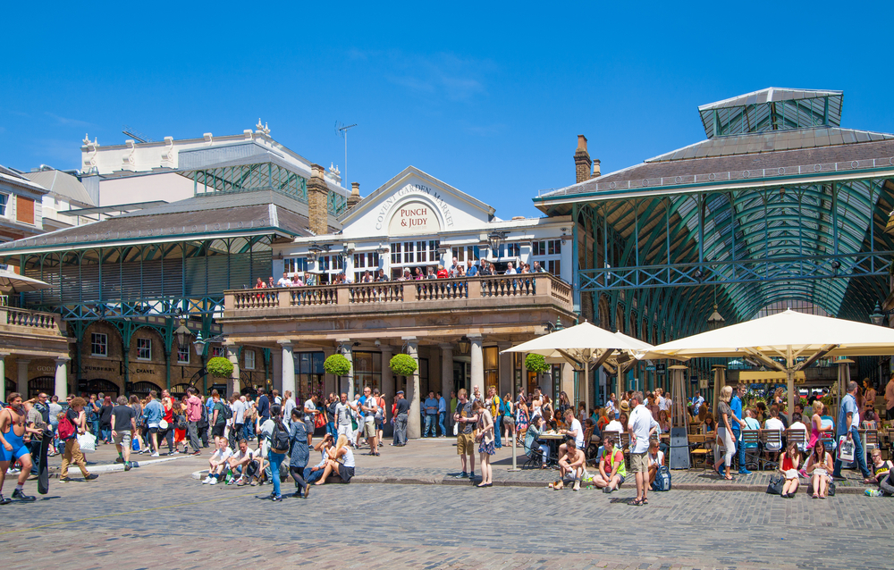 Crowds gather outside of the Covent Garden Market on a sunny day.