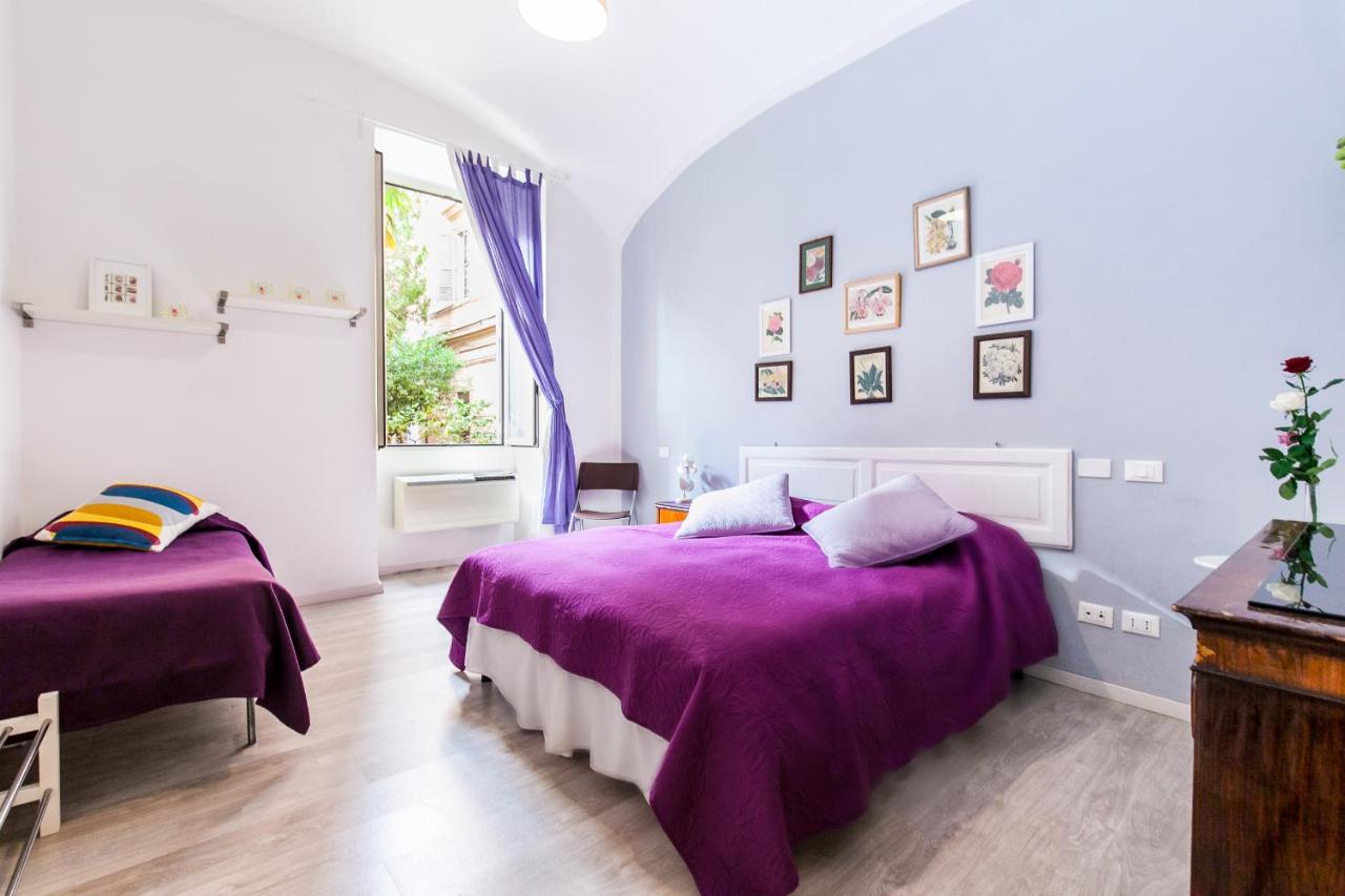 Room with two beds with purple bedspreads and prints on the wall.