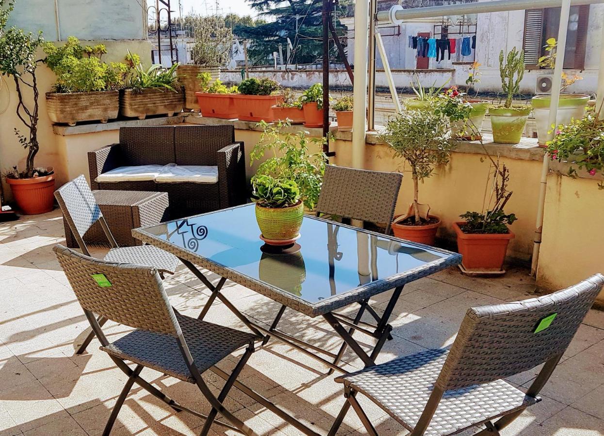 Sitting area on a sunny terrace with many potted plants.