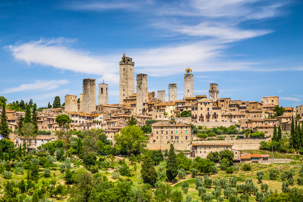 View of San Gimignano with many towers and trees outside the town.