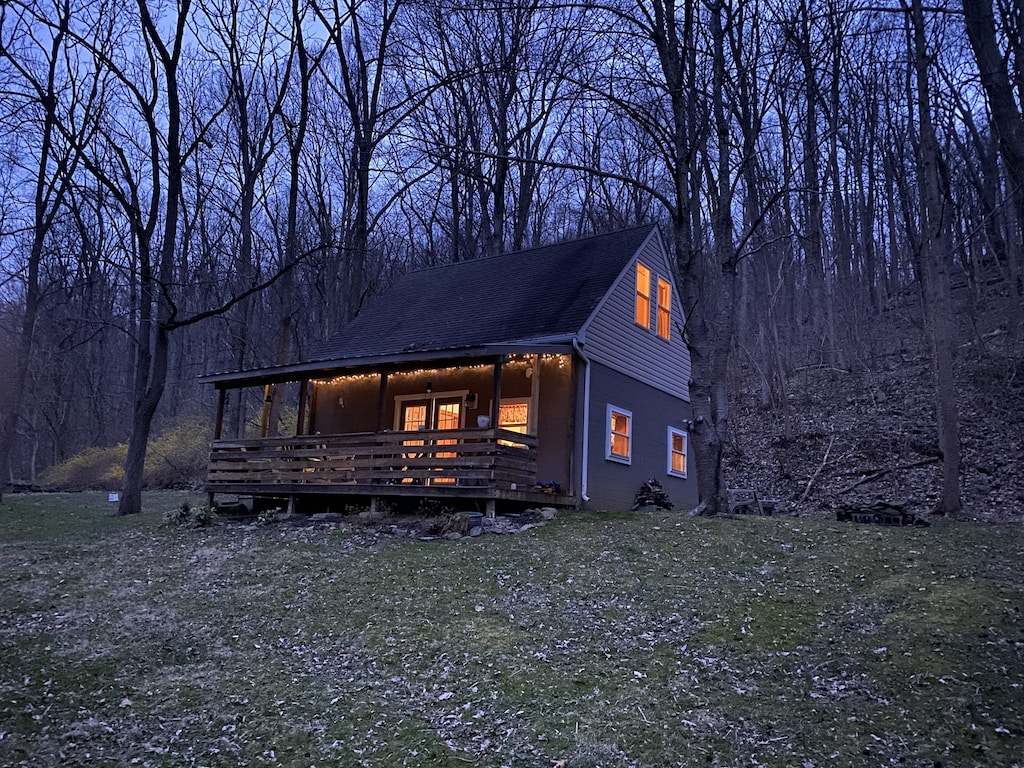 view of the exterior of the middle creek cabin at twilight, with twinkle lights on the porch and illuminated from within. 