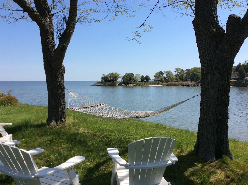 View of a hammock and two chairs overlooking the water at the waterfront cottage