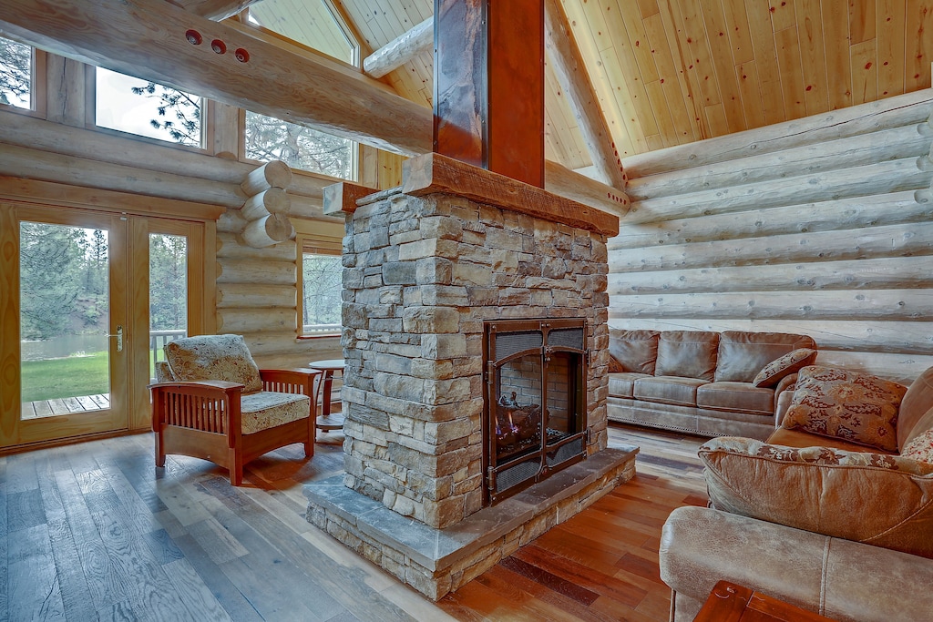 view of the double sided fireplace and charming stacked log interior of the Riverfront Log Cabin.