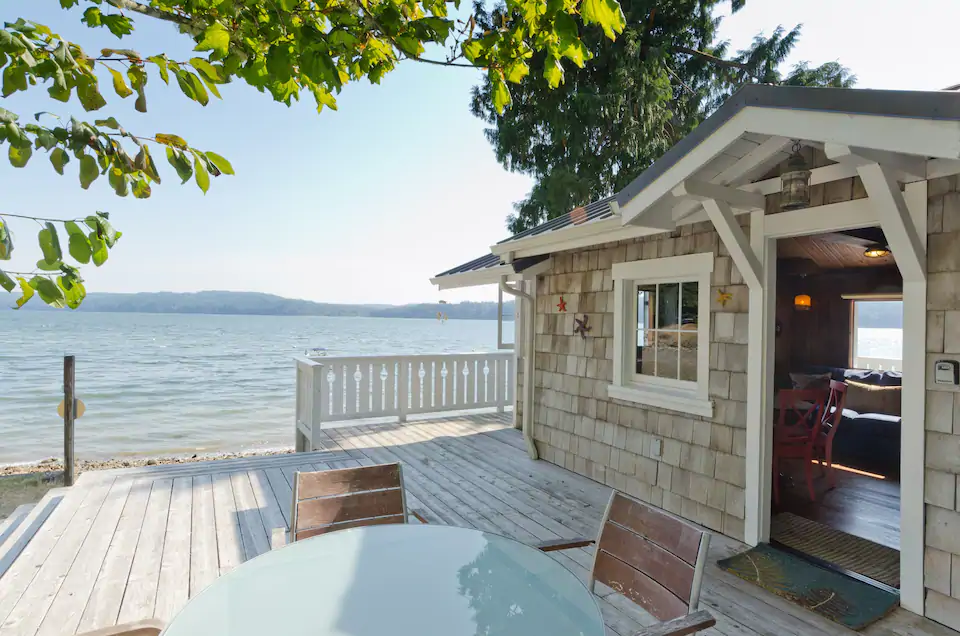 exterior view of the hood canal beach cabin including outdoor dining area and beautiful beach beyond. 