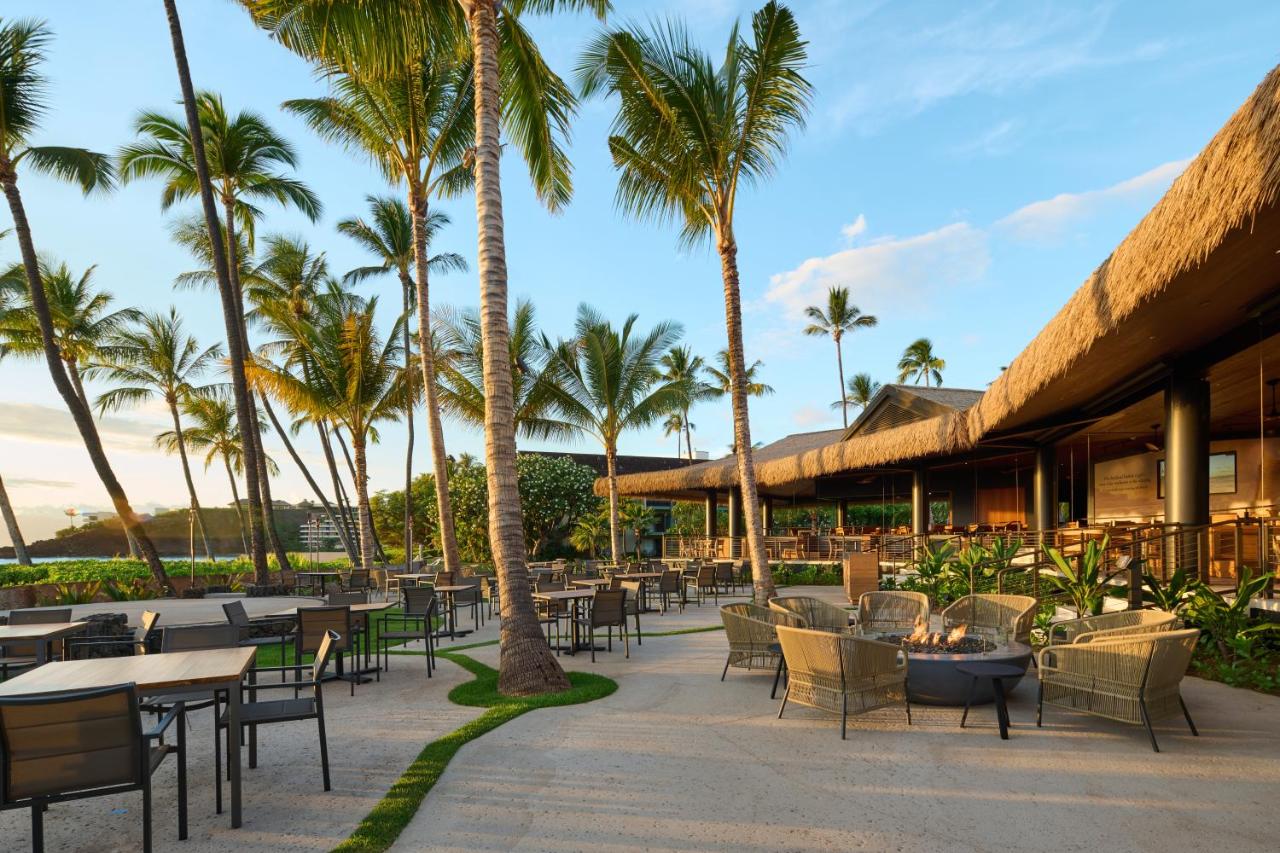 Outdoor lounge area with fire pits and palm trees.