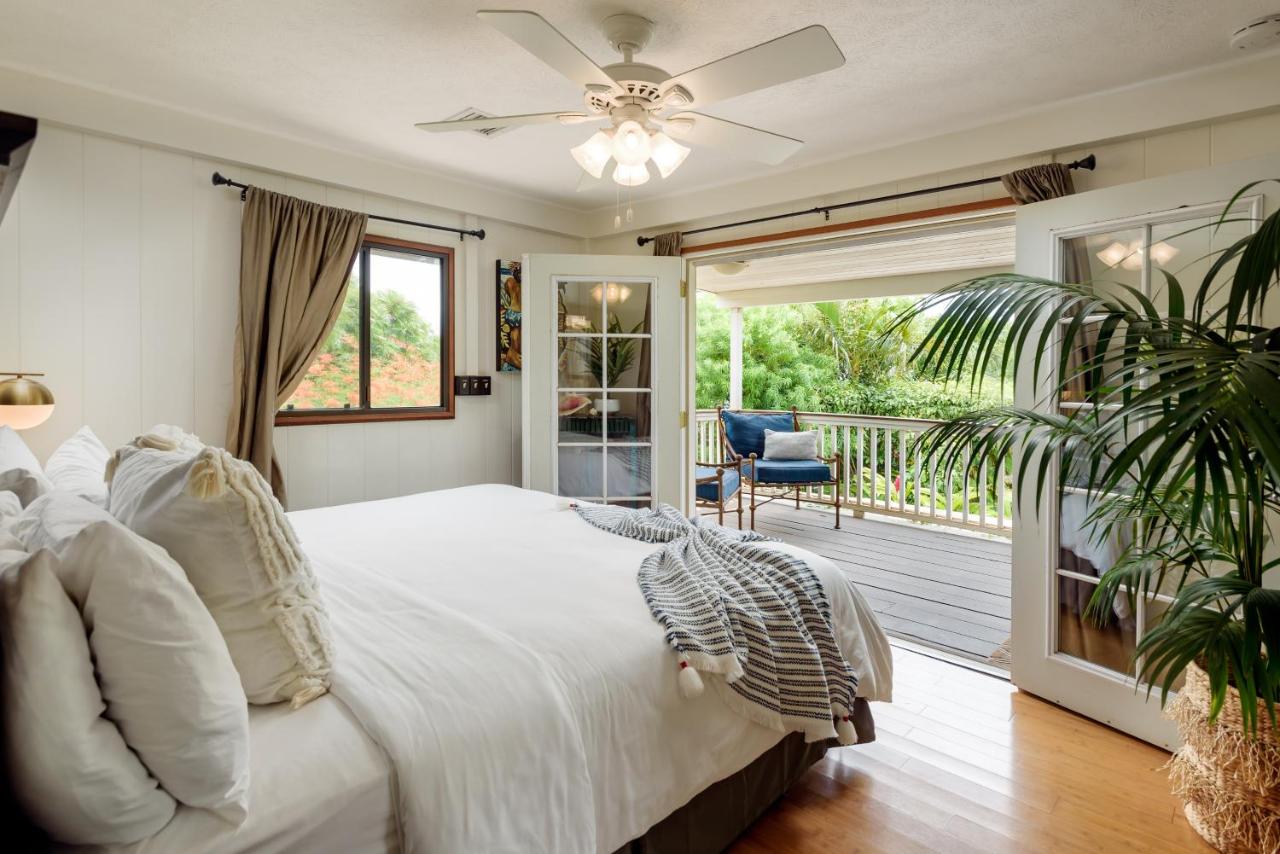 Bedroom at Paia Inn looking out at a balcony and lush garden.