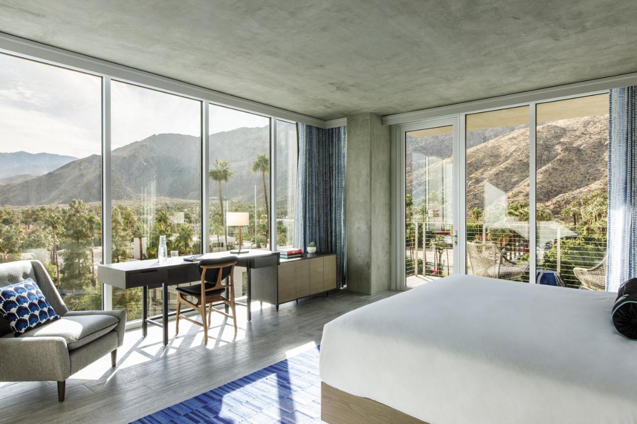 A modern resort suite with two walls of floor-to-ceiling windows that look out onto a mountain range