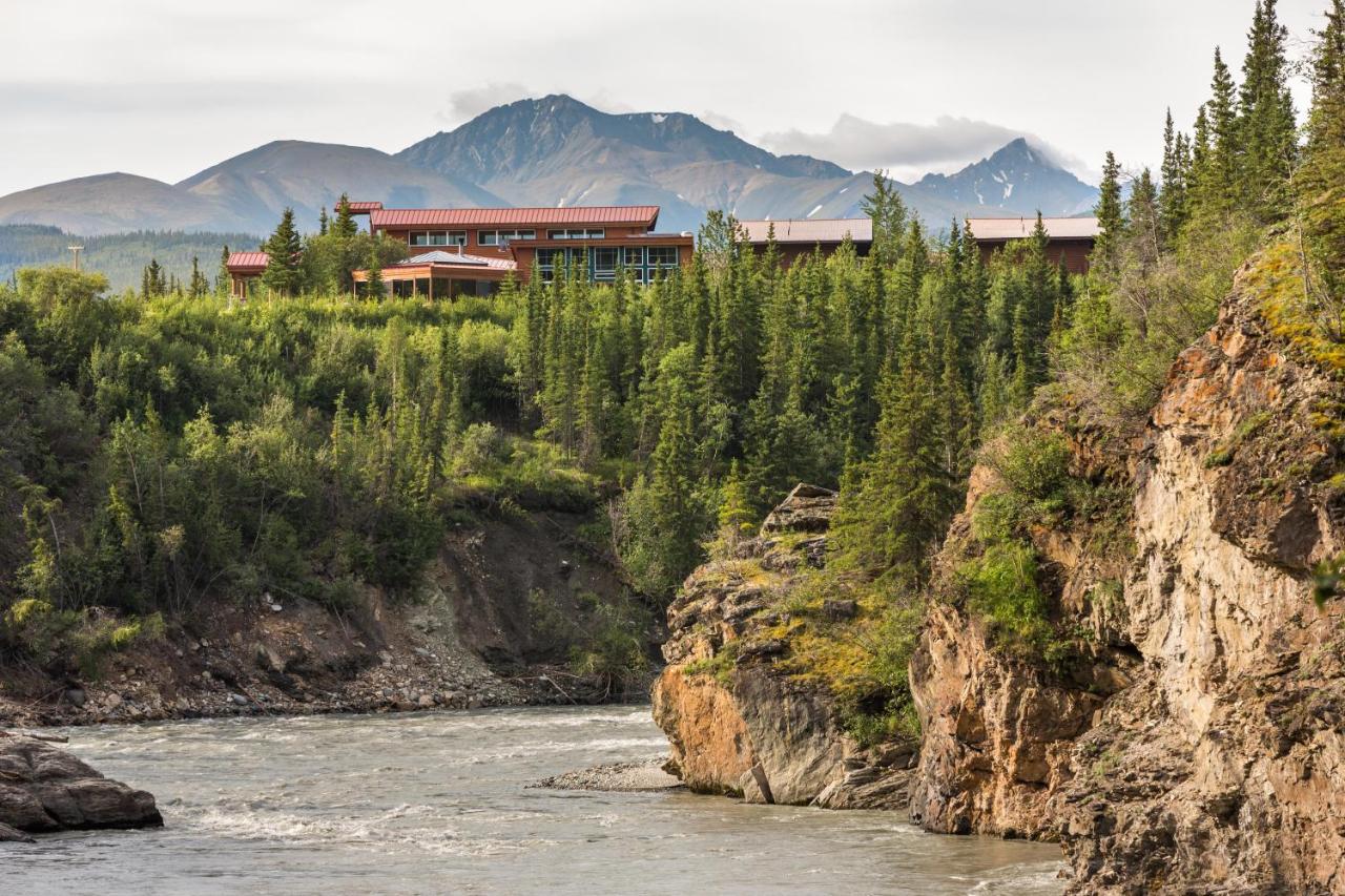 The view of a resort from the side of a rocky cliff on the edge of the ocean with mountains in the background