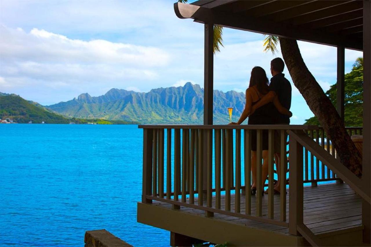 A couple standing on a balcony that looks out onto a large tropical mountain and the ocean at one of the best resorts on the West Coast